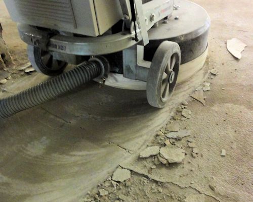 A diamond grinder preparing a concrete floor for epoxy coating